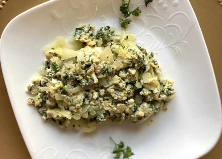 Egg white and parsley scramble served on a white plate and gold charger