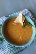 A bowl of Instant pot vegan red lentil soup with a chip and parsley