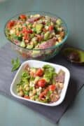 Large glass and small, square white bowl of avocado chickpea salad