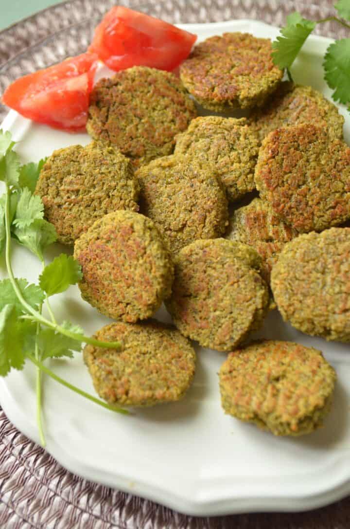 A plateful of gluten free falafel with a sprig of cilantro on a plate