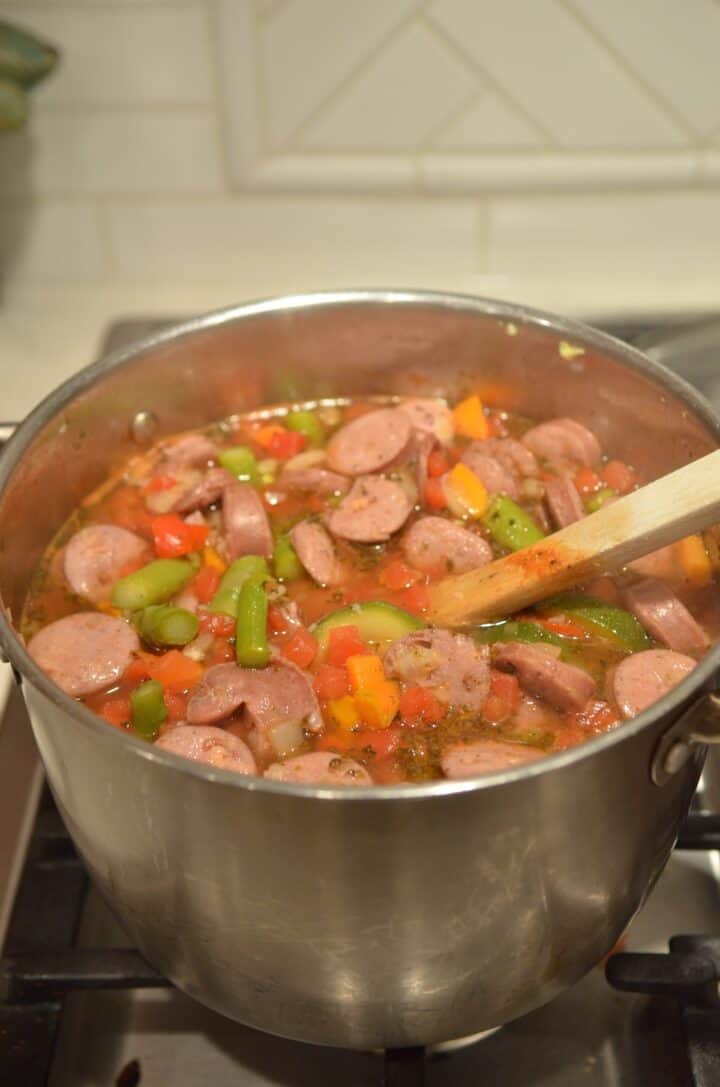 A pot of soup with chicken sausage and vegetables