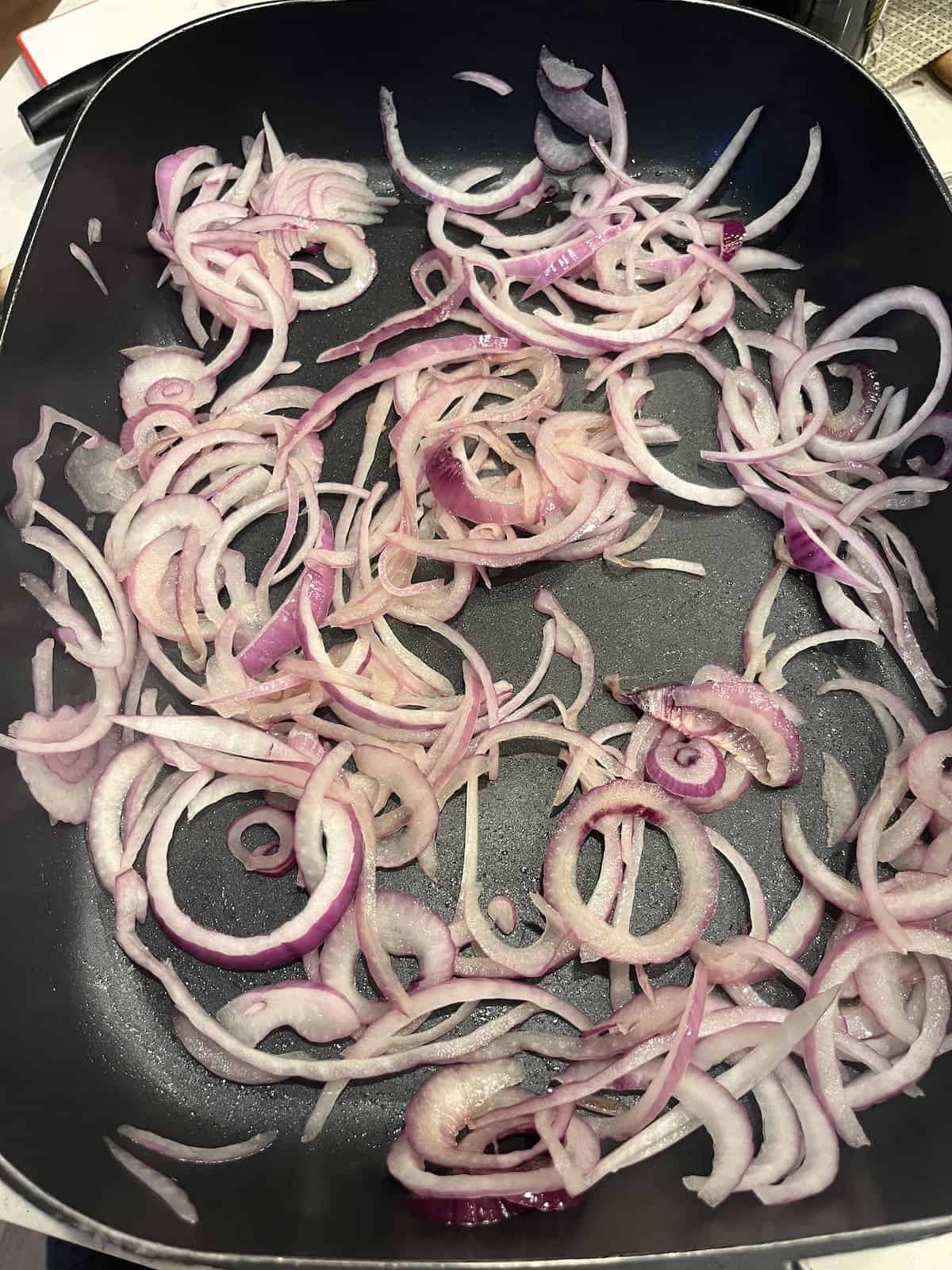 Caramelizing red onion in a pan.