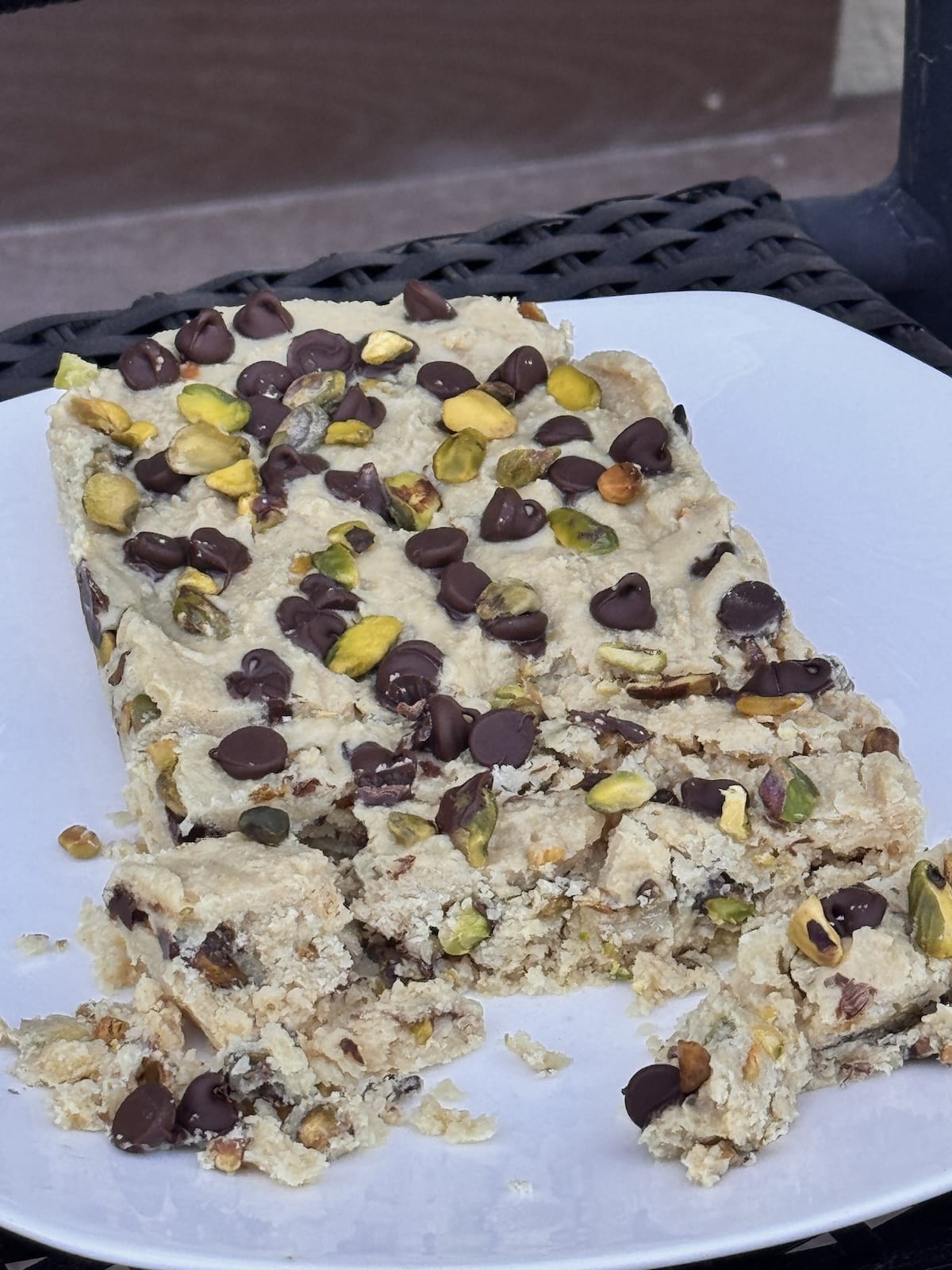 Pistachio halva with chocolate chips on a white plate.