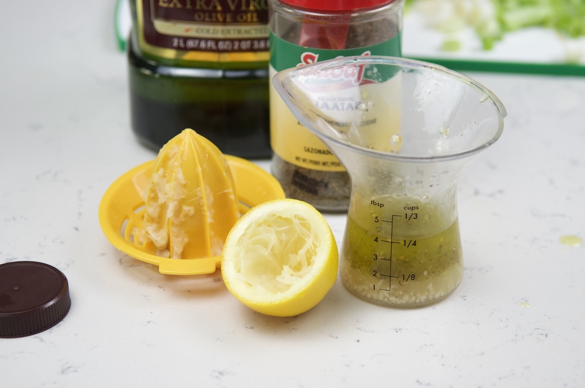 Dressing, next to a lemon, and a lemon squeezer.