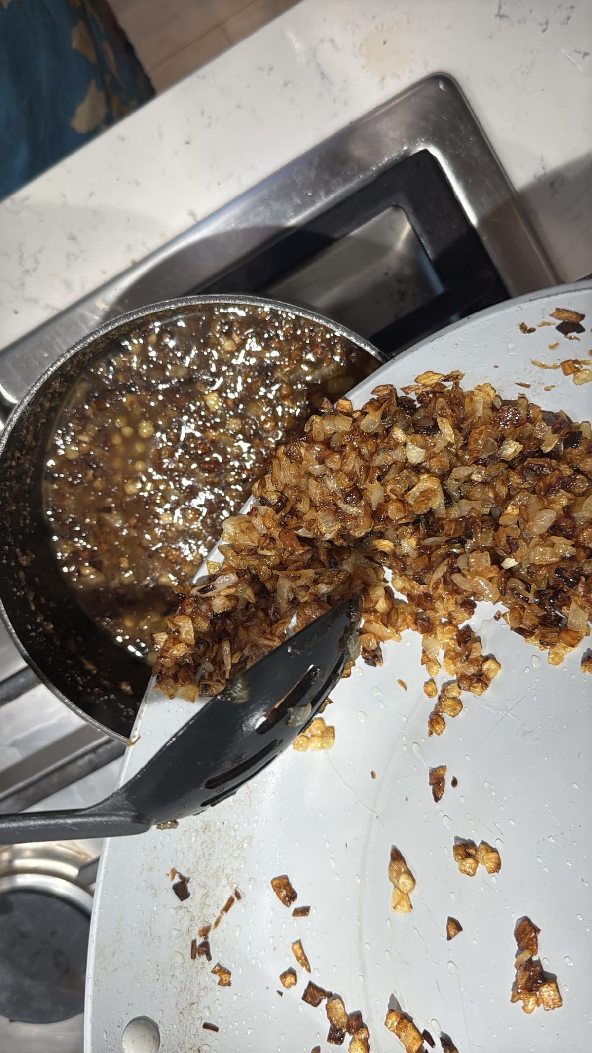 Spooning caramelized onions into pot with lentils.